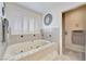 This bathtub features a decorative mirror, and tiled walls with neutral-colored mosaic tile at 5829 W Patrick Ln, Las Vegas, NV 89118