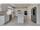 Modern white kitchen featuring stainless steel appliances, kitchen island and neutral tile floors at 681 Stone Hammer Ave, Las Vegas, NV 89183