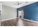 A neutral bedroom with a blue accent wall features wood floors, a ceiling fan and a window with natural light at 8021 Yellow Daisy Ave, Las Vegas, NV 89147
