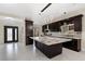 Spacious kitchen featuring an island, granite countertops, dark wood cabinets, and modern lighting at 8021 Yellow Daisy Ave, Las Vegas, NV 89147