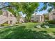Exterior view of condo buildings with well-maintained landscaping, green grass, mature trees, and stair access at 8409 Running Deer Ave # 203, Las Vegas, NV 89145
