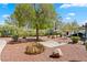 Landscaped front yard with mature tree, rock features, shrubs, and seating area offers an inviting outdoor space at 8409 Running Deer Ave # 203, Las Vegas, NV 89145
