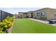 Lush backyard with artificial grass, a covered patio area, and vibrant yellow flowers adding charm at 8668 Hartmont St, Las Vegas, NV 89166