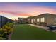 Dusk view of the backyard with artificial grass, covered patio, and cozy seating area at 8668 Hartmont St, Las Vegas, NV 89166