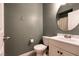 Bathroom with a gray wall, toilet, sink, and a round mirror at 9712 Red Horse St, Las Vegas, NV 89143