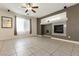 Bright living room features a fireplace, ceiling fan, and neutral tile flooring at 9712 Red Horse St, Las Vegas, NV 89143