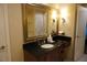 Bathroom vanity features a black countertop, wood cabinets, decorative mirror and lighting at 145 E Harmon Ave # 27621, Las Vegas, NV 89109