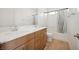 Well-lit bathroom features a double sink vanity with wood cabinets and modern fixtures and a bathtub with shower at 1474 Whistling Kite St, Las Vegas, NV 89138