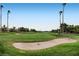 Picturesque view of a golf course with green fairway, sand trap, and distant palm trees at 1609 Hidden Spring Dr, Las Vegas, NV 89117
