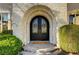 Elegant front entryway featuring arched stonework, a decorative iron door, and neatly trimmed shrubs at 2111 Bogart Ct, Las Vegas, NV 89117