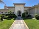 Inviting home entrance with a charming walkway, decorative shrubs, and an elegant archway framing the beautiful black double doors at 2111 Bogart Ct, Las Vegas, NV 89117