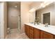 Bathroom featuring double sinks, wood cabinets, tile flooring, and glass enclosed shower at 2708 Cheer Pheasant Ave, North Las Vegas, NV 89084