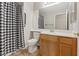 Well-lit bathroom with a white toilet, wood cabinet vanity, and shower with a stylish checkered curtain at 2812 Via Avanti St, Henderson, NV 89074