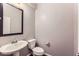 Modern half bathroom features a pedestal sink, toilet, and a framed mirror at 2878 Via Firenze, Henderson, NV 89044