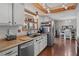 View of a kitchen with stainless steel appliances, white cabinetry, hardwood floors, and wooden ceiling beams at 3008 Soledad Dr, Laughlin, NV 89029