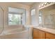 Bright bathroom featuring a soaking tub, single vanity, and views from a picture window at 301 Lakewood Garden Dr, Las Vegas, NV 89148