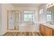 Bright bathroom featuring a glass shower, soaking tub, and views from a picture window at 301 Lakewood Garden Dr, Las Vegas, NV 89148