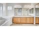 Bright bathroom featuring a double vanity, framed mirrors, soaking tub, and natural light at 301 Lakewood Garden Dr, Las Vegas, NV 89148