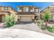 Two-story home featuring a two-car garage, desert landscaping, and a brick driveway with sidewalk access at 330 Spring Dove Ave, Henderson, NV 89011