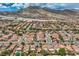 Expansive aerial view of a vibrant community with terracotta roofs and lush landscaping against a stunning mountain backdrop at 3412 Crystal Tower St, Las Vegas, NV 89129
