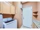 Well-lit laundry room featuring front-load washer, cabinets, and access door at 3412 Crystal Tower St, Las Vegas, NV 89129