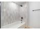 Contemporary bathroom featuring a bathtub with gray and white tiling and a rainfall shower head at 3459 One Nation Ave, Las Vegas, NV 89121