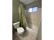 Bathroom featuring a shower-tub combo with olive-green shower curtain, toilet, and light tile flooring at 445 Sam Jonas Dr, Las Vegas, NV 89145