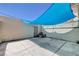 Concrete patio area featuring blue sunshade, door, and privacy wall, perfect for outdoor entertaining at 4693 Mill Valley Dr, Las Vegas, NV 89120