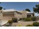 A single-story beige home featuring a two-car garage, desert landscape, and gated yard at 471 Fallwood Ln, Las Vegas, NV 89107