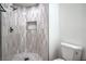 Beautiful walk-in shower featuring unique tilework and a built-in shelf, next to a standard toilet at 5321 Marietta Ave, Las Vegas, NV 89108