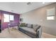 View of the bedroom reveals comfortable gray sofa, glass desk and purple accent wall at 6940 Crescent Gold St, North Las Vegas, NV 89086
