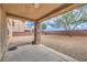 A covered patio and a spacious backyard filled with desert landscaping including gravel and a tree at 7095 Mountain Den Ave, Las Vegas, NV 89179