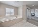 Luxurious main bathroom featuring a large soaking tub with jacuzzi jets by a window at 7095 Mountain Den Ave, Las Vegas, NV 89179