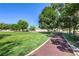 Scenic park area with lush green grass, mature trees, and a paved walking path at 7460 Buckskin Ave, Las Vegas, NV 89129