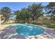 Backyard swimming pool with rock features surrounded by mature trees at 7460 Buckskin Ave, Las Vegas, NV 89129