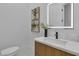 Modern bathroom featuring a marble countertop, wood cabinets, and a stylishly lit mirror at 7738 Willow Cove Cir, Las Vegas, NV 89129