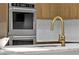 Close up of new gold faucet on large marble countertop and stainless oven at 7738 Willow Cove Cir, Las Vegas, NV 89129