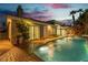 Backyard pool with spa surrounded by a brick patio, landscaping and exterior lights at twilight at 7738 Willow Cove Cir, Las Vegas, NV 89129