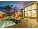 Backyard pool and spa with patio, palm trees and exterior lights at twilight at 7738 Willow Cove Cir, Las Vegas, NV 89129