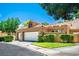 Charming home featuring a tile roof, two-car garage and manicured landscaping with vibrant green shrubs at 8236 Round Hills Cir, Las Vegas, NV 89113