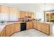 Bright kitchen with wooden cabinets, black appliances, and natural light from a large window at 8236 Round Hills Cir, Las Vegas, NV 89113
