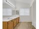 Bathroom featuring a vanity with storage, wood-look floors, a large mirror, and plenty of natural light at 9535 Stills Way, Las Vegas, NV 89148