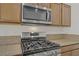 Close-up view of kitchen's stainless steel microwave and gas range with stone countertops at 9535 Stills Way, Las Vegas, NV 89148