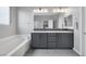 Elegant bathroom featuring double sinks, a large mirror, modern lighting, and a soaking tub at 9876 Heather Moore Ave, Las Vegas, NV 89166