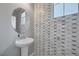 Modern powder room showcasing stylish wall tiles, a pedestal sink, and a round mirror at 9876 Heather Moore Ave, Las Vegas, NV 89166