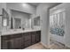 Bathroom featuring dual sinks, dark wood cabinets, a large mirror, and a shower-tub combo at 10116 Skye Castle Dr, Las Vegas, NV 89166