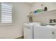 Laundry room featuring white appliances and a shelf stocked with cleaning supplies at 1017 Pebble Lake St, Henderson, NV 89011