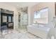 Elegant bathroom featuring marble shower, soaking tub, and stylish chandelier at 11912 Skyline Arch Ct, Las Vegas, NV 89138