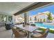 Covered patio featuring a dining table overlooking the pool and water feature, creating a relaxing outdoor retreat at 11912 Skyline Arch Ct, Las Vegas, NV 89138