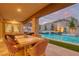 Outdoor patio area with dining and lounge seating overlooking a sparkling pool and manicured landscaping at 11912 Skyline Arch Ct, Las Vegas, NV 89138